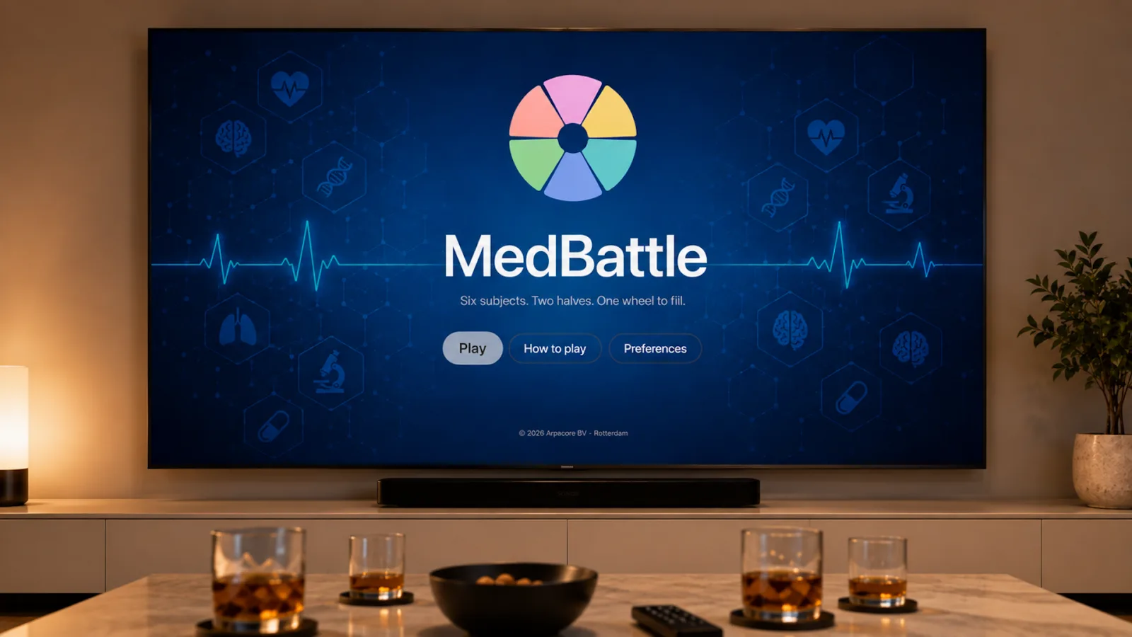 MedBattle on an Apple TV in a living room: the six-wedge wheel logo above the title and the tagline “Six subjects. Two halves. One wheel to fill.”, with Play, How to play and Preferences buttons